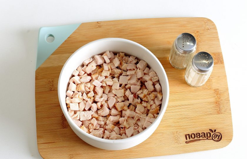 1. Этап. Салат с копченой грудкой и сыром: Куриное филе нарежьте мелкими кубиками и выложите первым слоем. Смажьте грудку майонезом.