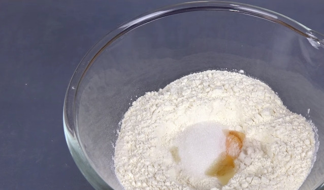 1. Этап. Хлеб на сковороде: 1. Муку (примерно половину от общего количества) просейте в глубокую ёмкость. По центру сделайте углубление. Вбейте туда яйцо. Добавьте соль и сахар.