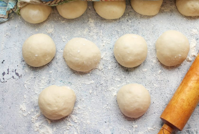 1. Этап. Пирожки с солеными груздями и рисом: Подошедшее тесто разделите на одинаковые кусочки и сформируйте шарики. Разложите их на посыпанном мукой столе на расстоянии. Накройте тесто и дайте постоять 10-15 минут, чтобы заготовки подошли.