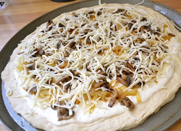 1. Этап. Пицца со сливочным соусом: 11. Натрите моцареллу на терке, посыпьте поверх лука и грибов.