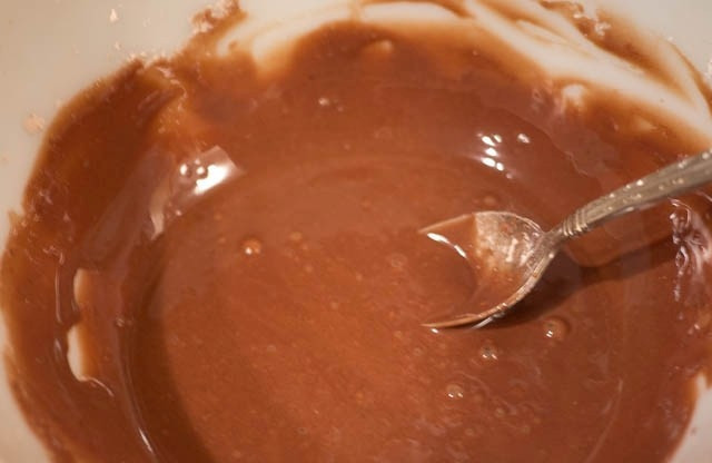 1. Этап. Шоколадная глазурь для пончиков: Влейте воду и варите на медленном огне. Чтобы получилась гладкая глазурь, нужно постоянно помешивать массу.