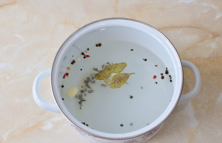 1. Этап. Сало варёное с чесноком: В кастрюлю налейте воду. Добавьте соль, перец, лавровый лист, пару зубчиков чеснока и специи. Поставьте на огонь и доведите до кипения.