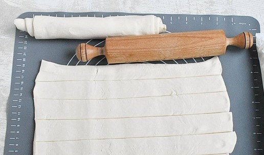 1. Этап. Слоеные корзиночки с чизкейком: 2. Слегка раскатайте тесто в одном направлении, не нарушая слоев. Одну половинку нарежьте тонкими полосками. Вторую скрутите в плотный рулет.