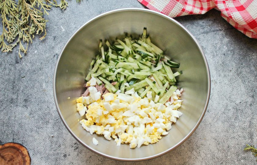 1. Этап. Салат Мясное ассорти: Яйцо почистите от скорлупы, порежьте кубиком и добавьте к мясу и ветчине. У огурца отрежьте кончики, порежьте соломкой и добавьте в салатник.