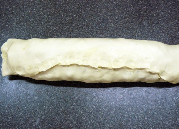 1. Этап. Яблочный штрудель из готового слоеного теста: Движением от себя сверните из теста с начинкой рулет. Скрепите аккуратно и плотно края теста.