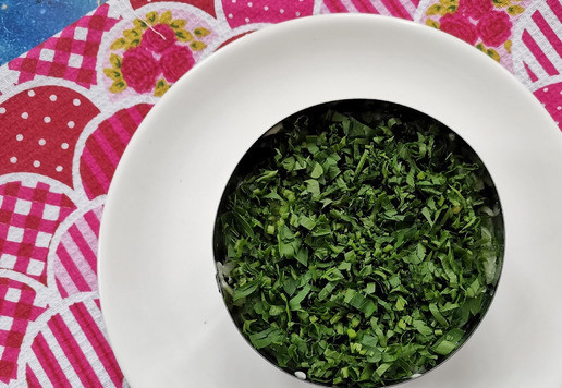 1. Этап. Слоёный рыбный салат Лето: Мелко порубить петрушку и уложить поверх огурца.