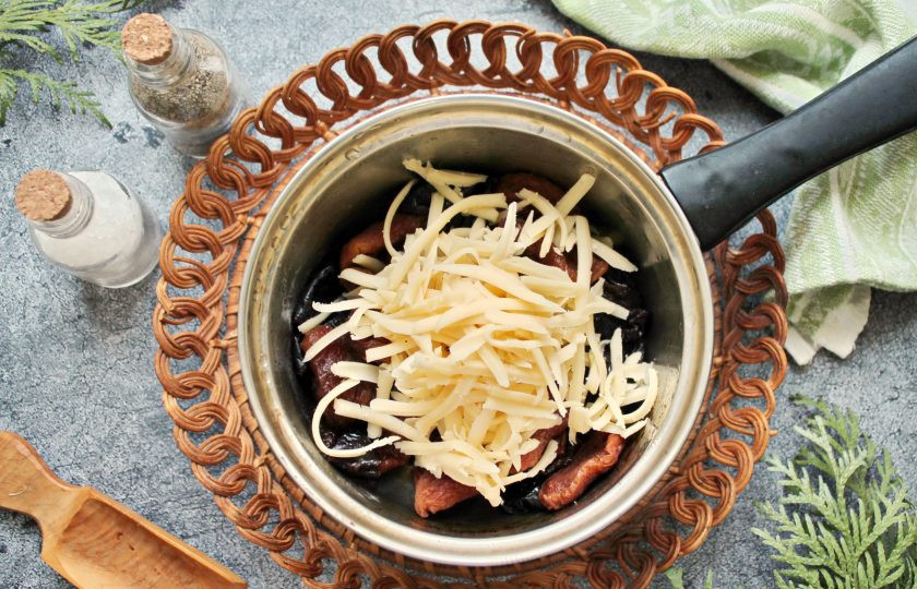 1. Этап. Гармошка из свинины с курагой, черносливом и сыром: В остывшие сухофрукты выложите 2/3 натертого сыра и перемешайте.