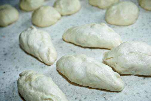 1. Этап. Тесто на пирожки жареные: Поднявшееся тесто нужно обмять 1 раз и оставить его еще на столько же времени в тепле. Так оно наберет силу и окрепнет. В общей сложности мы ждем около двух часов. По истечении времени разделяем тесто на комочки. Каждый комочек сплющиваем и растягиваем вручную. Скалка в данном случае нам не понадобится. Кладем на тесто начинку, защипываем края. Оставляем налепленные пирожки на 10 минут, чтобы немного поднялись.