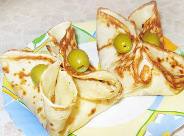 1. Этап. Блины с ветчиной: 5. Захватить края блинов пальцами и закрепить с помощью зубочистки. Нанизать на зубочистки оливки и подавать.