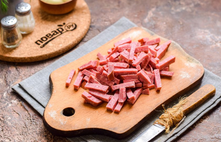 1. Этап. Салат Мужской каприз с колбасой: Копченую колбасу нарежьте тонкими полосками.