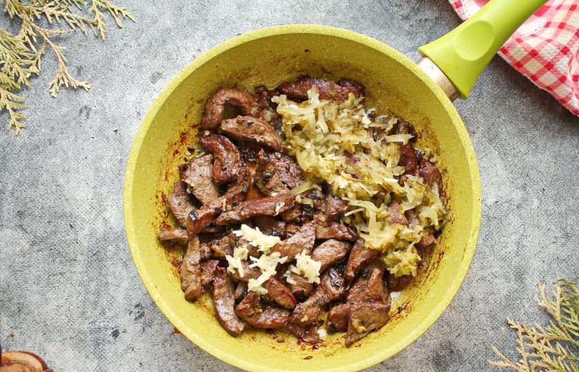 1. Этап. Печень с гарниром: Чеснок измельчите, соленые огурцы порежьте тонкой соломкой или натрите на крупной терке, добавьте в сковороду. Все хорошо перемешайте.