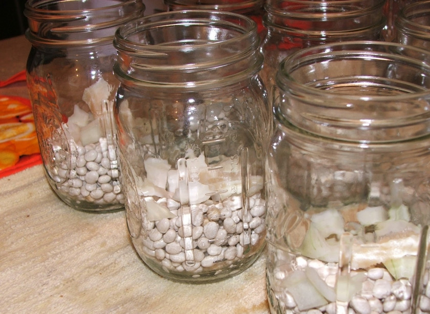 1. Этап. Консервированная фасоль в томатном соусе: Промойте и переберите сухую фасоль. Залейте её водой на ночь, чтобы разбухла. На следующий день отварите до полуготовности. Распределите по стерилизованным банкам (у меня было 8 пол-литровых банок). Лук почистите, порежьте кубиками и добавьте в каждую банку (по 2-3 ст.л. примерно получается).