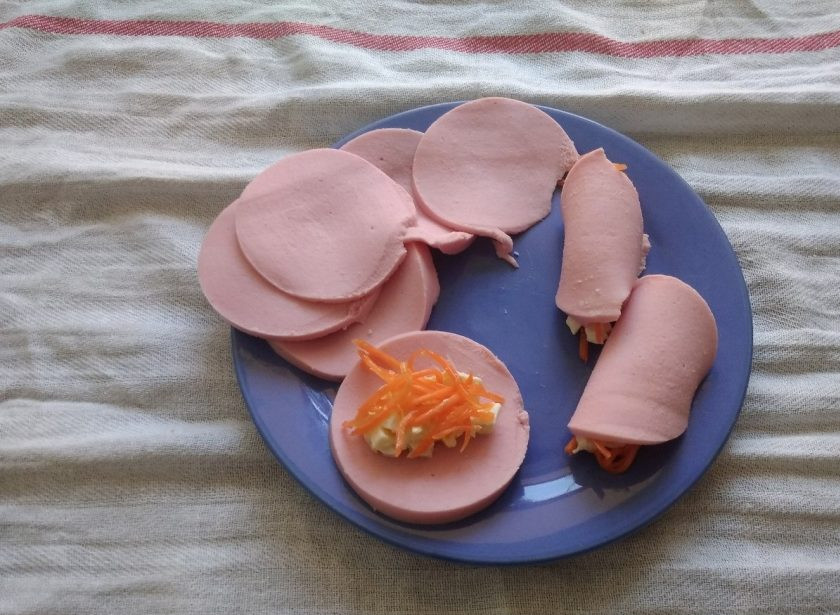 1. Этап. Рулетики из колбасы с начинкой: 6. Теперь на каждый ломтик выложите часть начинки. Сверху немного моркови.