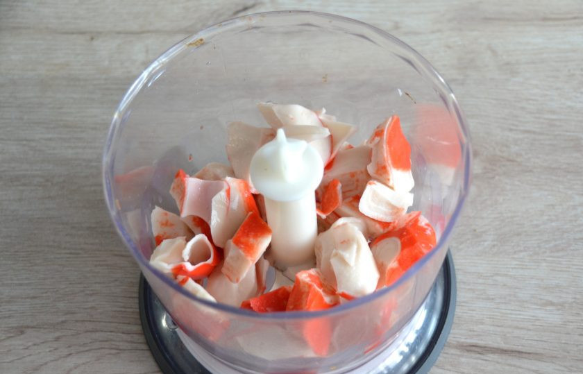 1. Этап. Профитроли без глютена: Пока выпекаются профитроли, займитесь приготовлением начинки. Выложите крабовые палочки в блендер и измельчите до однородности.