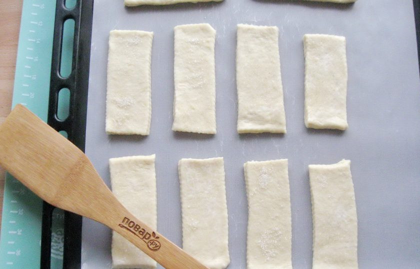 1. Этап. Слоеные язычки на пиве: Нарежьте тесто на язычки. Выложите на противень. Отправьте в духовку, заранее разогретую до 185-190 градусов.