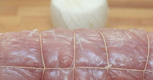 1. Этап. Праздничный рулет из свинины с начинкой: 4. Аккуратно сверните рулет, перевяжите плотной ниткой. Второй половиной смеси из чеснока, масла и сока лимона со специями обмажьте рулет со всех сторон. Отправьте в разогретую до 200 градусов духовку.