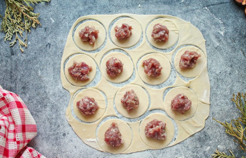 1. Этап. Пельмени из кабана: Тесто тонко раскатайте на столе с мукой и вырежьте кружочки подходящей выемкой. Разложите по кружочкам фарш из кабана.