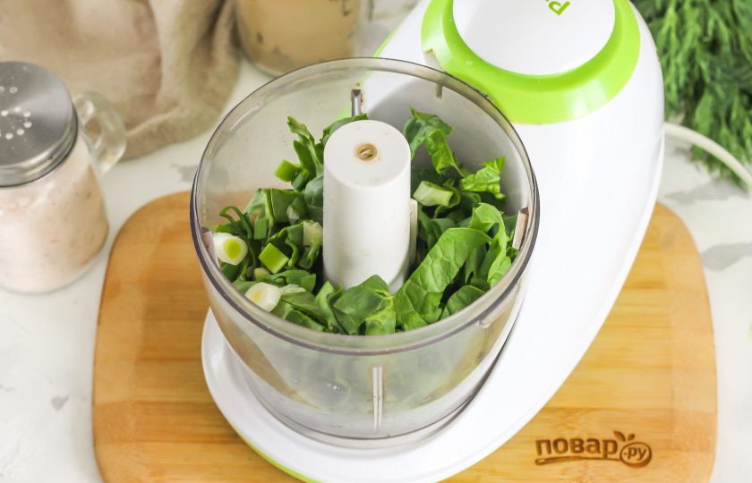 1. Этап. Соус к жареным пельменям: Промойте листья шпината в воде, срежьте стебли и нарежьте лентами, выложите в чашу измельчителя. Промойте стебли зеленого лука и измельчите, всыпьте к шпинатной нарезке.