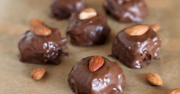 1. Этап. Конфеты Баунти (простой рецепт): Выложите конфетки на противень, застеленный пергаментной бумагой, и на каждую уложите по одному миндальному ореху. Дайте конфетам застыть при комнатной температуре.