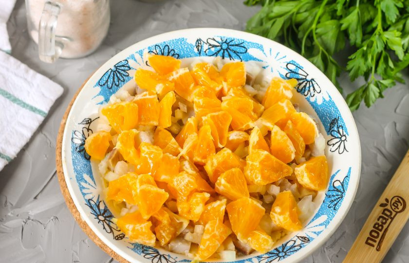 1. Этап. Селедка под шубой с мандаринами: Нарежьте половину очищенной луковицы мелким кубиком и выложите на слой сельди. Очистите от кожуры мандарины и нарежьте ломтики кубиками, удаляя косточки. Выложите на слой лука. Фруктовый сок замаринует лук и придаст ему сладости.