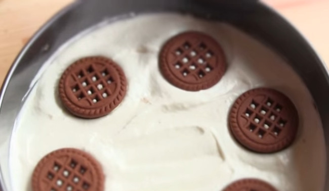 1. Этап. Чизкейк без выпечки с творогом: 7. Отправьте часть начинки в форму, разровняйте, затем выложите печенье и снова покройте начинкой. Чередуйте так слои. Накройте пищевой пленкой и поставьте на 2 часа в холодильник.