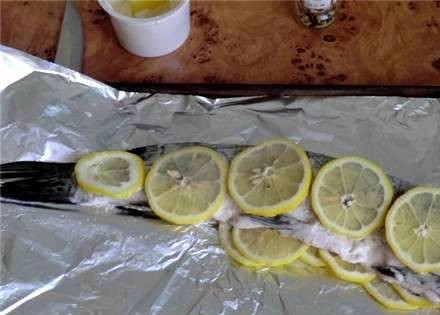 1. Этап. Щука со сметаной в духовке: Внутрь рыбы и на ее поверхность выкладываем ломтики лимона.