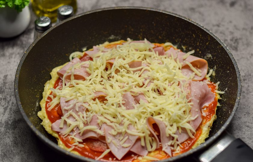 1. Этап. Быстрая пицца на сковороде из лаваша с яйцом: Поверх посыпьте все тертым твердым сыром. Готовьте под крышкой 5-7 минут на небольшом огне.