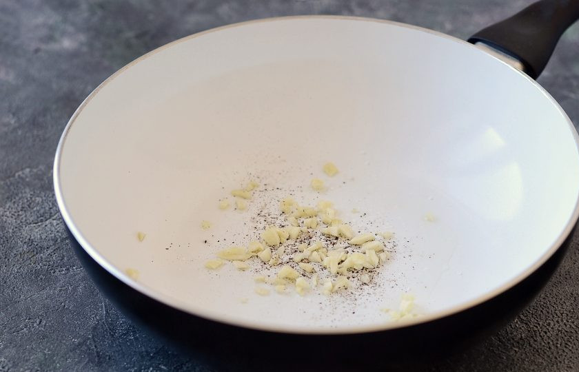 1. Этап. Постная паста с грибами: Разогрейте сковороду с маслом. Добавьте соль, перец и мелко рубленый чеснок. Обжарьте 20-30 секунд до раскрытия аромата.