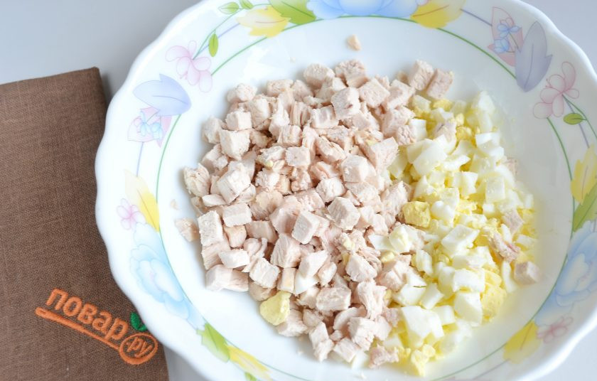 1. Этап. Салат на Новый год 2025: 2. Яйца охладите и очистите от скорлупы. Порежьте яйца и филе кубиками.