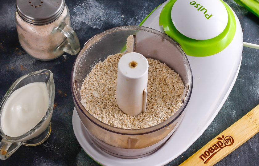 1. Этап. Полезные ватрушки с творогом: Овсяные хлопья быстрого приготовления измельчите в чаше блендера, превращая практически в муку, в мелкую крошку.