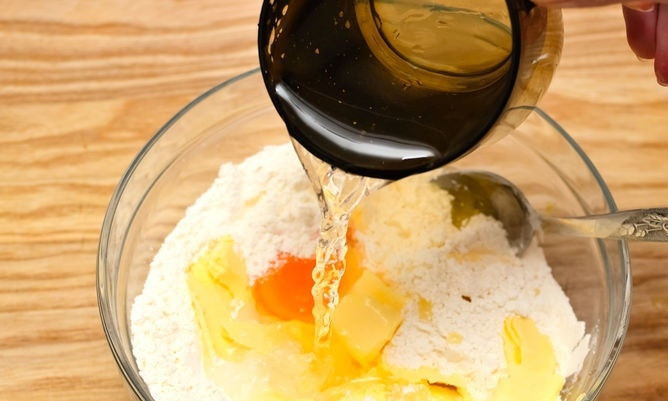 1. Этап. Быстрый лимонный пирог: 3. Вбейте желток, всыпьте сахар и влейте ледяную воду (сперва немного, по мере необходимости можно добавлять). Начните вымешивать тесто.