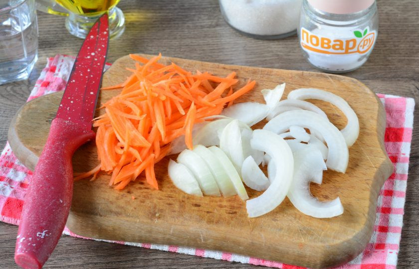 1. Этап. Капуста с огурцами по-корейски на зиму: Натрите на терке морковку, а лук нарежьте полукольцами.