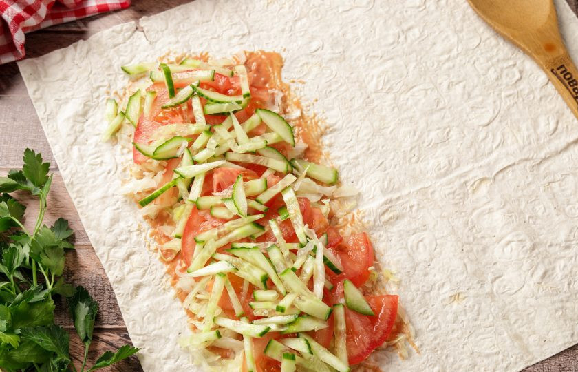 1. Этап. Шаурма в аэрогриле: Если у вас большой лаваш, его можно разрезать на две части. У меня обычный квадратный, одну часть которого смажьте соусом и выложите овощи.