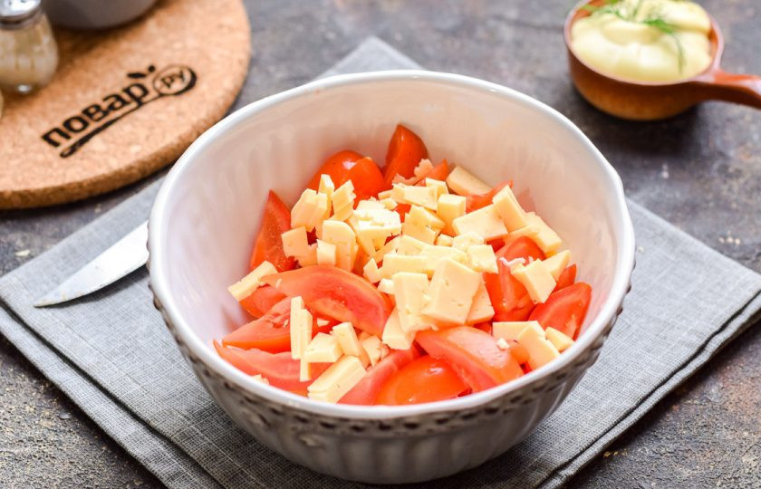 1. Этап. Салат Кайфовый с крабовыми палочками: Помидоры и палочки переложите в салат. Сыр нарежьте небольшими кубиками и добавьте в салат.