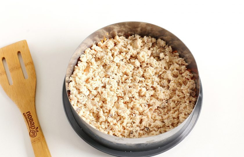 1. Этап. Салат Французская мимоза: Консервированную горбушу достаньте из масла, удалите крупные косточки и раздавите вилкой. Выложите горбушу на морковь, разровняйте ложкой. Этот слой можно присыпать солью.