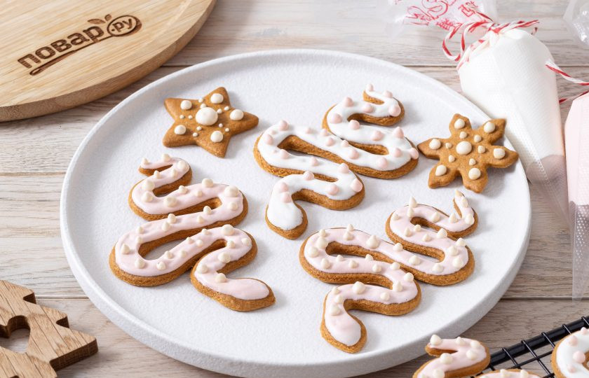 1. Этап. Имбирное печенье на Новый год Змеи: Переложите глазурь в кондитерский мешок, отрежьте кончик. Нанесите глазурь на печенье. Можно покрыть их полностью или нарисовать узоры. Оставьте высохнуть глазурь.