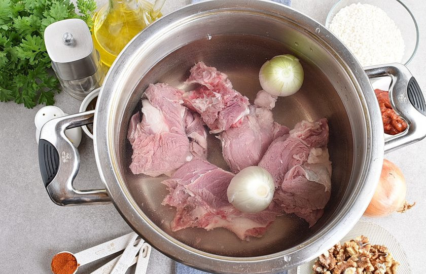 1. Этап. Харчо из говядины с ткемали: Мясо промойте, нарежьте крупными кусками и поставьте варить бульон. После закипания тщательно снимите пену, добавьте очищенную луковицу, разрезанную пополам, немного посолите и варите на минимальном огне до готовности мяса.