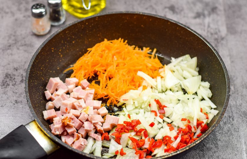 1. Этап. Суп Острый: Пока варится картофель, очистите лук и морковь. Нарежьте лук мелкими кубиками, морковь натрите на мелкой терке. Острый перец нарежьте мелко, бекон нарежьте кубиками. Разогрейте сковороду и влейте немного масла, выложите лук, морковь, перец, бекон и жарьте несколько минут.