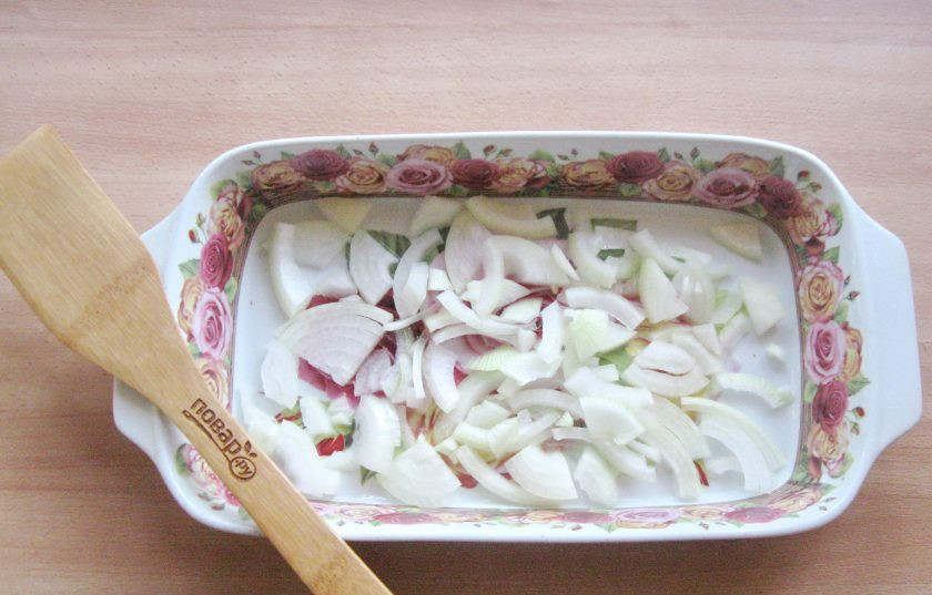 1. Этап. Карп в духовке на луковой подушке: Одну крупную луковицу или две средние очистите, помойте и нарежьте полукольцами или четверть кольцами. Выложите в форму для запекания, смазанную подсолнечным маслом.