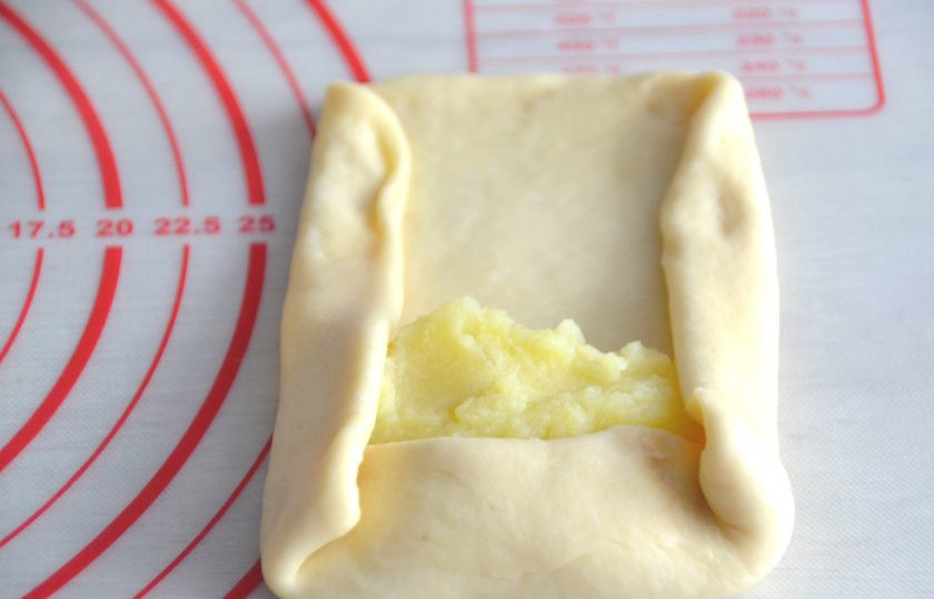 1. Этап. Пирог из рулетиков с разными начинками: Раскатайте кусочек теста в овальную лепешку, выложите на край картофельную начинку, подверните края, скатайте в рулет.