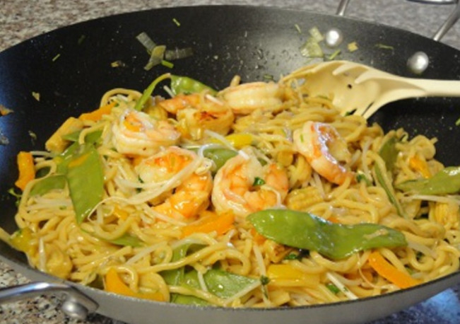 1. Этап. Вок с креветками: 4. Добавляем в вок лапшу и перемешиваем. Смешиваем куриный бульон с соевым соусом, соком лайма, добавляем крахмал, соль и сахарный песок, перемешиваем и поливаем полученной смесью лапшу с овощами. Готовим еще несколько минут.