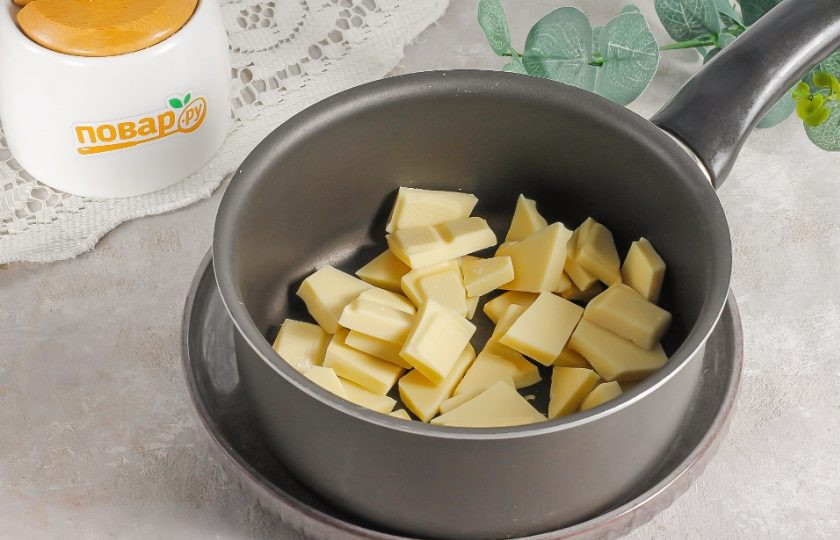 1. Этап. Взбитый ганаш на белом шоколаде: Удалите обертки шоколада и разломите его на кубики. Выложите их в ковш или в глубокую емкость, если будете прогревать шоколад на водяной бане. Если у вас есть сноровка, то можно прогреть шоколад в ковше, но он не должен свернуться. Поместите емкость на плиту и протомите на минимальном нагреве буквально 1-2 минуты. Вам не нужно расплавлять его полностью, а нужно лишь прогреть до расплавления.