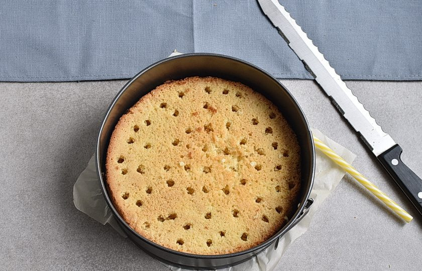 1. Этап. Торт с ягодами: Достаньте корж на решетку и остудите до теплого состояния. Срежьте верхний купол и переверните торт обратно в форму. Палочкой диаметром с мизинец проткните корж по всему объему.