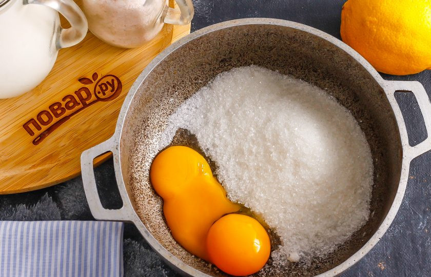 1. Этап. Наполеон с лимонным кремом: Отделите желтки от белков, разбив куриные яйца. Выложите желтки в казан или ковш с антипригарным дном. Белки в рецепте не понадобятся. Всыпьте сахар.