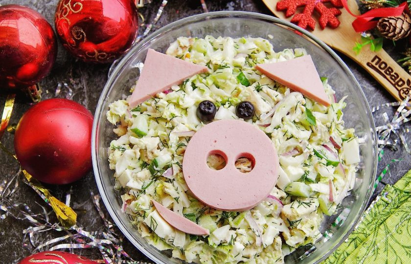 1. Этап. Новогодний салат Пятачок: Переложите салат в салатник, вырежьте из вареной колбасы пятачок и ушки, офорите блюдо в виде свинки. В качестве глаз подойдут маслины или подходящие замороженные ягоды. Салат 