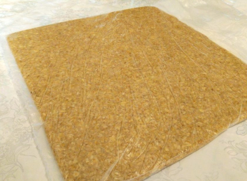 1. Этап. Геркулесовые пирожные: Поместите готовое тесто в плотный пакет и распределите внутри, помогая себе скалкой. Пласт должен быть длиной примерно 20-25 см и шириной - 15-20 см. Поместите пакет с тестом в морозилку для застывания (10-15 минут).