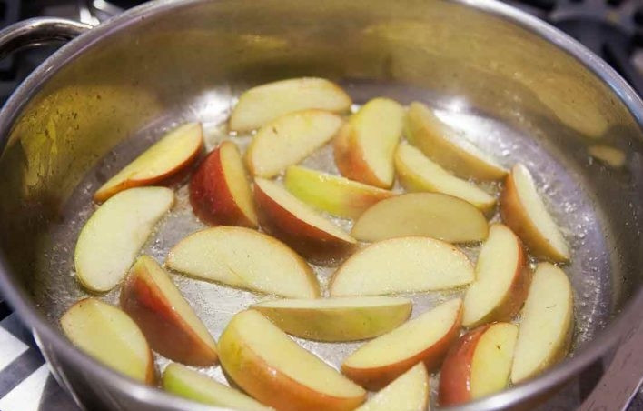 1. Этап. Куриные окорока с соусом: 1. Мясо вымойте и оботрите, затем посолите и оставьте на 20-30 минут. Тем временем нарежьте яблоки ломтиками. Разогрейте сковороду с 2-мя столовыми ложками сливочного масла, выложите яблоки в один слой и обжаривайте до появления золотистой корочки. Переложите готовые яблоки в тарелку.