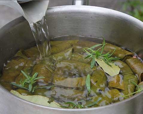 1. Stage. Dolma: First, close the stuffing by bending the upper edges of the sheet. Then close the filling with the sides of the sheet and roll up a tight tube, like cabbage roll. In the same way, cook the remaining dolma. Put 2 layers of grape leaves at the bottom of a thick-bottomed pan. Put dolma close to each other, seam down. Pour in water flush with dolma .