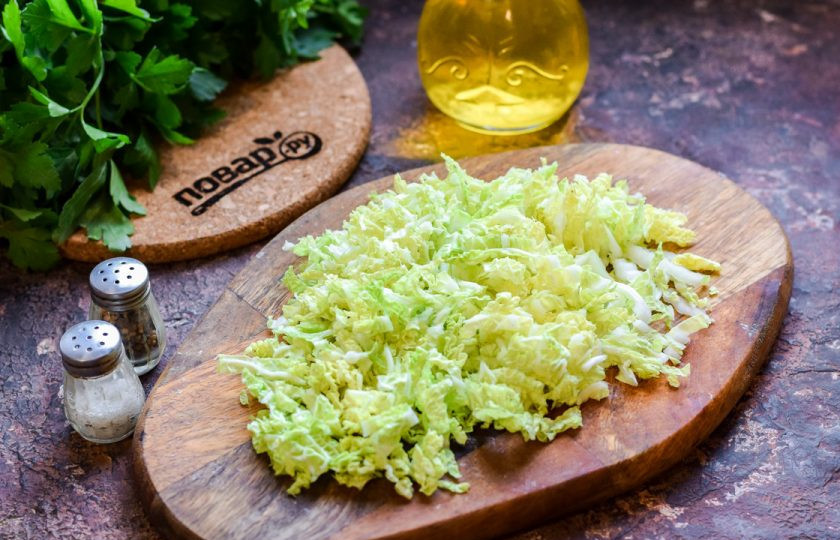 1. Этап. Простой салат из китайской капусты: Китайскую капусту ополосните и просушите, разрежьте вдоль на две половины. Нарежьте капусту тонкими полосками.