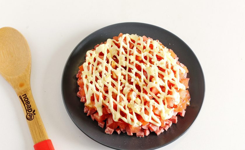 1. Этап. Салат с копчёной колбасой: Посолите слой и поперчите по вкусу. Сделайте сверху сеточку из майонеза и посыпьте все измельченным чесноком.